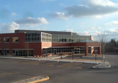 The front of a large building with a parking lot.
